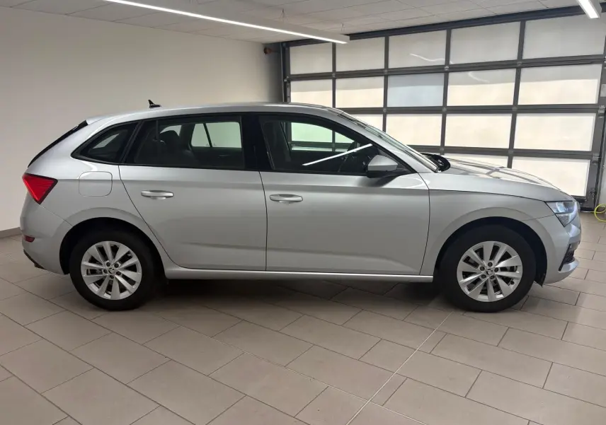 Vue de profil côté gauche d'une Skoda Scala gris argent 2024 en version 1.0 TSI 110 DSG7 Business stationnée en intérieur.