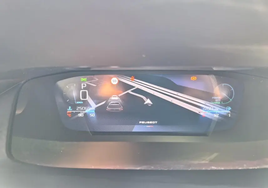 Affichage numérique du cockpit de la Peugeot 308 SW Hybrid 145 GT montrant la vitesse, navigation et indicateurs divers.