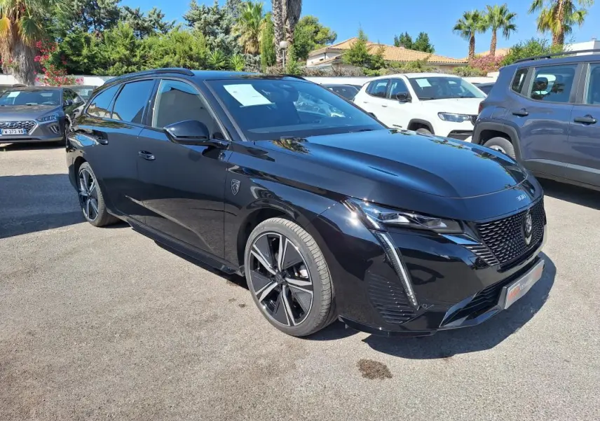 Peugeot 308 SW Hybrid 145 GT noir vue 3/4 avant avec barres de toit et jantes alliage 18 pouces.