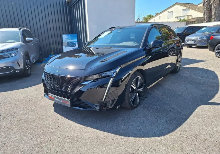 Peugeot 308 SW Hybrid 145 e-DCS6 GT noir vue 3/4 avant avec barres de toit et jantes alliage 18 pouces.