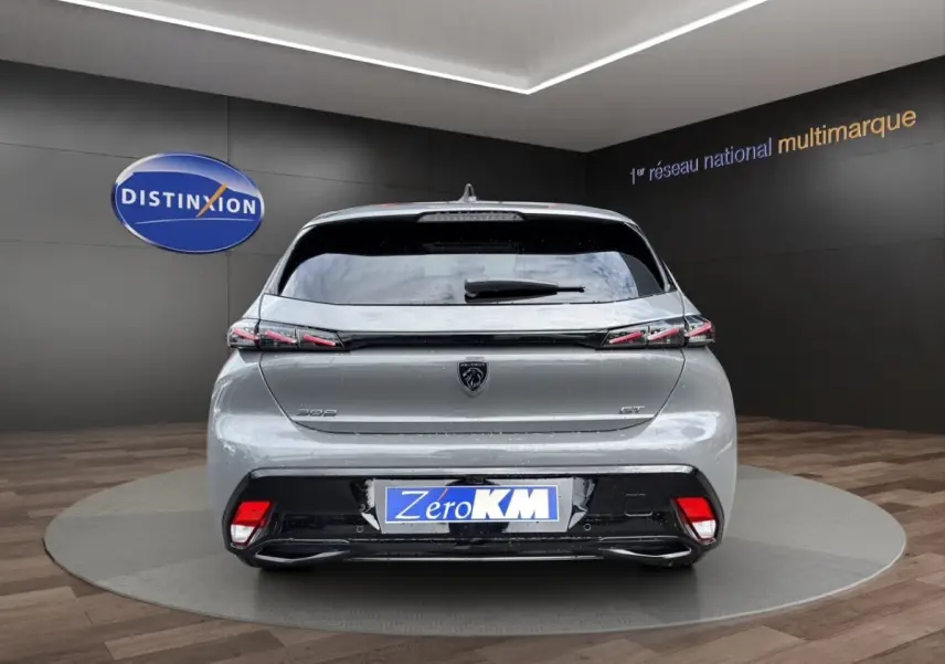Vue arrière d'une Peugeot 308 GT gris clair avec feux LED et logo lion au centre du hayon.