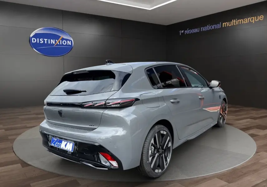 Peugeot 308 gris clair vue 3/4 arrière droit, avec feux arrière LED et jantes alliage distinctives.