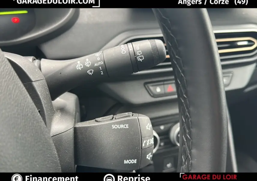 Gros plan sur la commande de clignotants et le volant noir du Dacia Jogger Extreme+ Hybrid 2025, intérieur sombre.