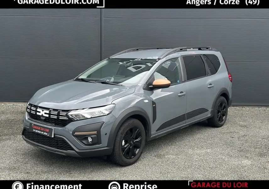 Vue 3/4 avant d’un Dacia Jogger Extreme+ Hybrid 140 gris avec rétroviseur couleur cuivre et jantes noires.