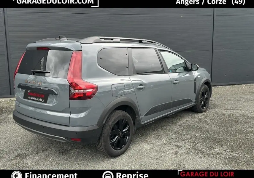 Vue 3/4 arrière droite d'un Dacia Jogger Extreme+ Hybrid 140 gris avec jantes noires et vitres teintées.