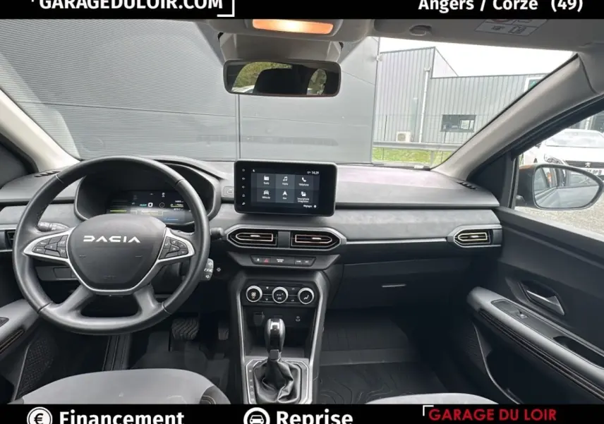 Vue intérieure avant du Dacia Jogger Extreme+ Hybrid 140 2025, tableau de bord gris avec écran tactile central et volant multifonction.