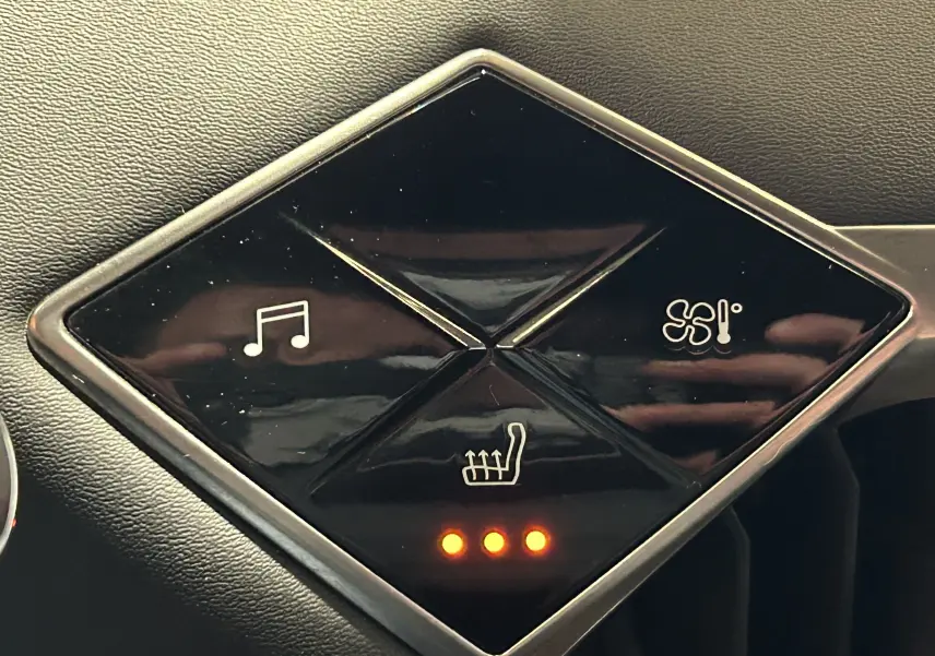 Gros plan sur les commandes tactiles noires du tableau de bord du DS3 Crossback Bleu Millenium, avec indicateurs lumineux allumés.