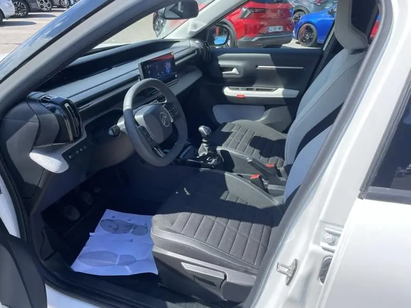 Intérieur de la Citroën C3 Nouvelle 2025 blanc, vue côté conducteur avec tableau de bord moderne et boîte manuelle.