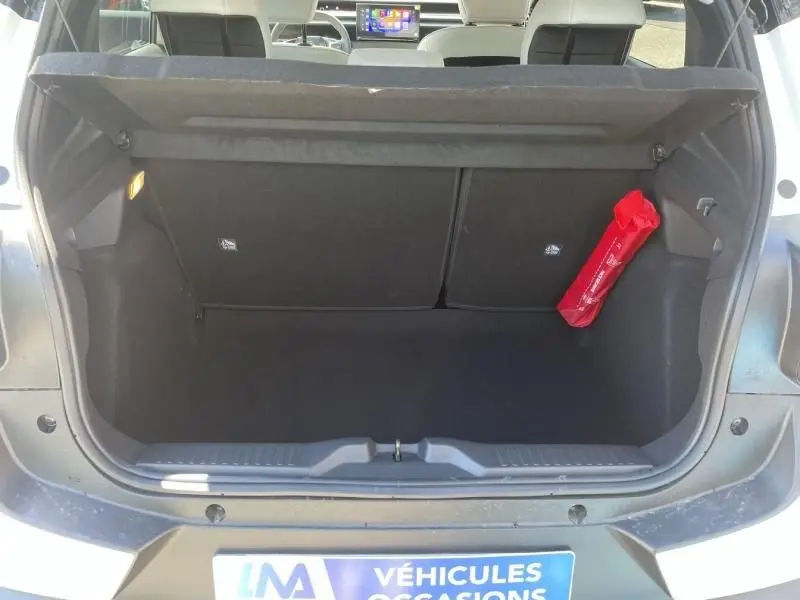 Coffre ouvert vu de l'arrière d'une Citroën C3 Nouvelle blanche 2025, avec un triangle de signalisation rouge fixé sur le côté.