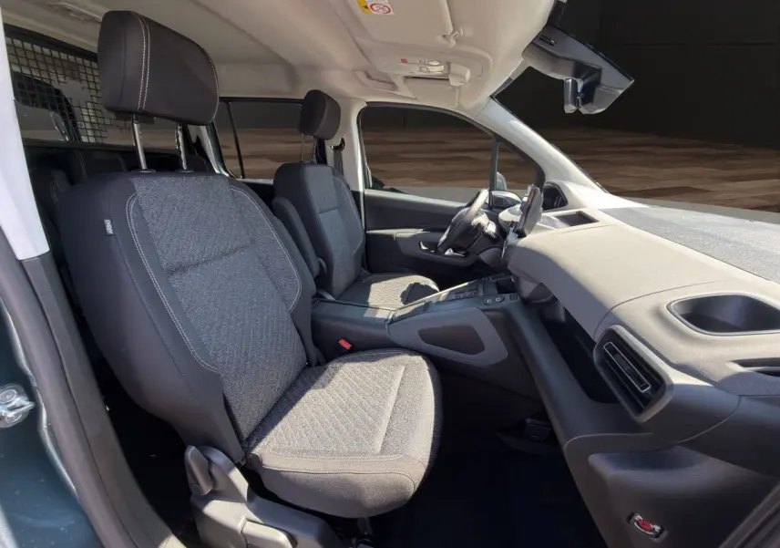 Vue intérieure côté droit du Peugeot Rifter 2026, sièges tissu gris et tableau de bord moderne avec écran tactile.