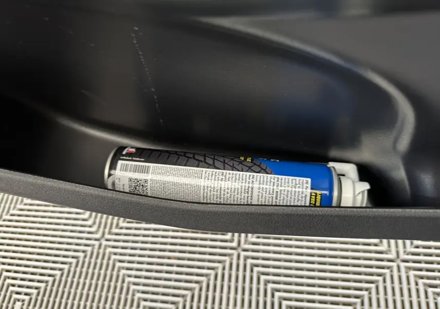 Gros plan sur le rangement de porte côté gauche d'une Aixam Ambition 0.5 City Pack bleu avec bombe anti-crevaison.