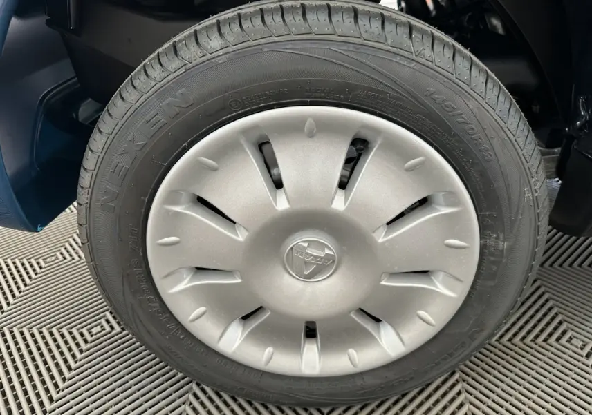 Gros plan sur la roue avant droite d'une Aixam Ambition 0.5 City Pack bleu avec jante argentée et logo central.