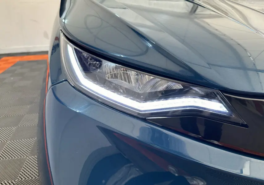 Gros plan sur le phare avant gauche d'une Aixam Ambition 0.5 City Pack bleu 2025 avec éclairage LED distinctif.