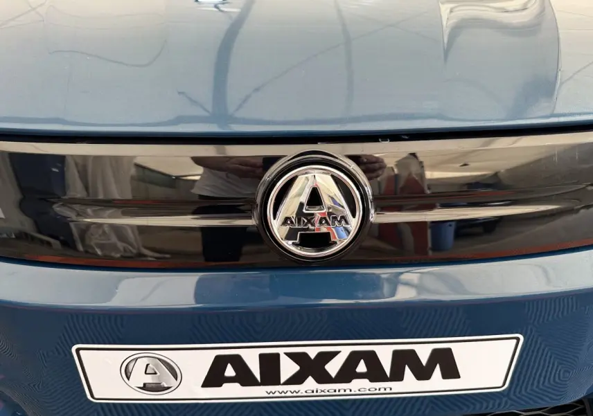 Gros plan sur la calandre avant bleue de l'AIXAM AMBITION 0.5 CITY PACK avec logo central chromé.