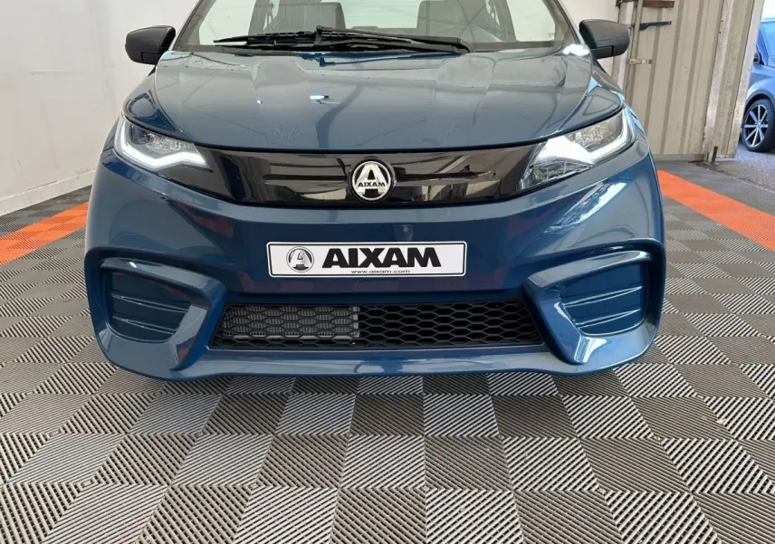 Vue frontale d'une Aixam Ambition 0.5 City Pack bleu 2025 avec calandre noire brillante et logo central visible.