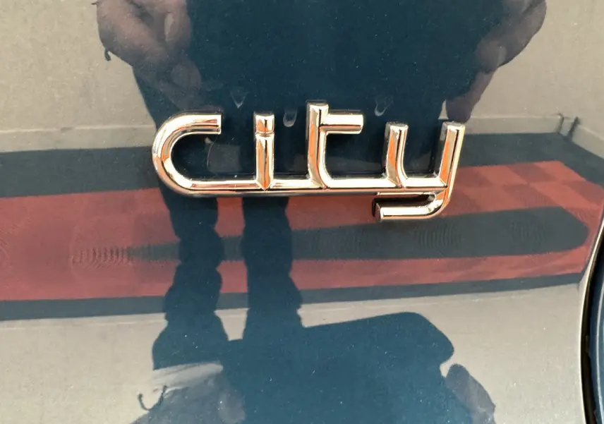Gros plan sur l’inscription chrome "city" sur la carrosserie bleue de l’AIXAM AMBITION 0.5 CITY PACK 2025.