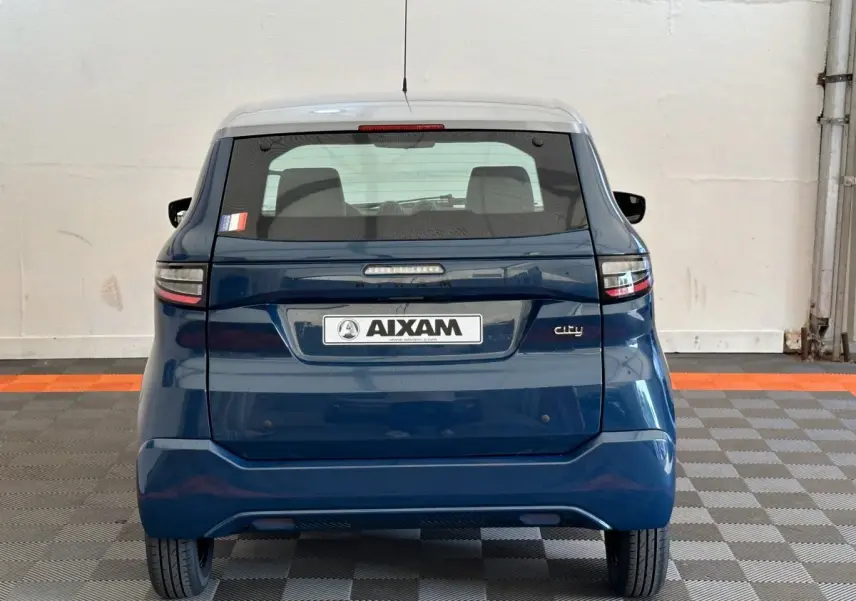 Vue arrière d'une Aixam Ambition 0.5 City Pack bleu 2025 avec rétroviseur caméra côté gauche visible.
