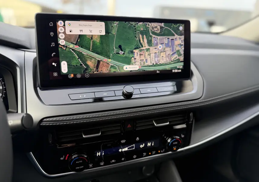 Vue rapprochée de la console centrale du Nissan Qashqai 2025 gris, avec écran tactile affichant une carte GPS.