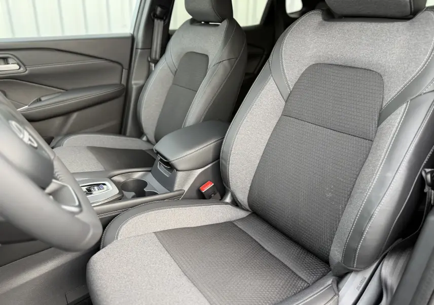 Vue intérieure rapprochée des sièges avant gris clair et noir avec surpiqûres blanches du Nissan Qashqai 2025.
