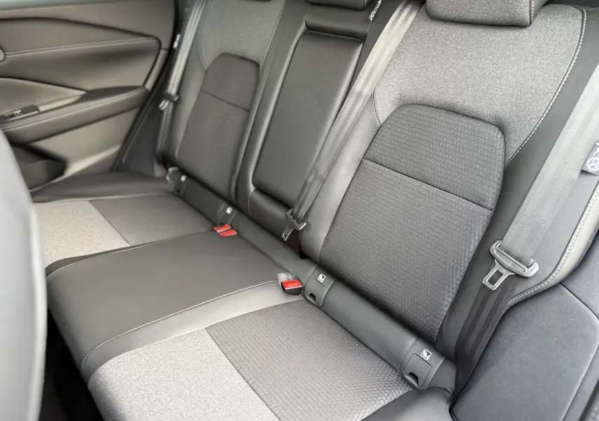 Vue rapprochée des sièges arrière en tissu noir et gris du Nissan Qashqai 2025, avec ceintures de sécurité visibles.