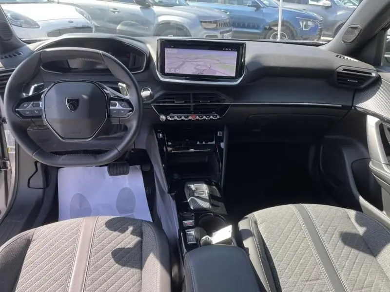 Vue intérieure avant du Peugeot 2008 1.2 Hybrid gris métal, avec tableau de bord numérique et écran tactile central.