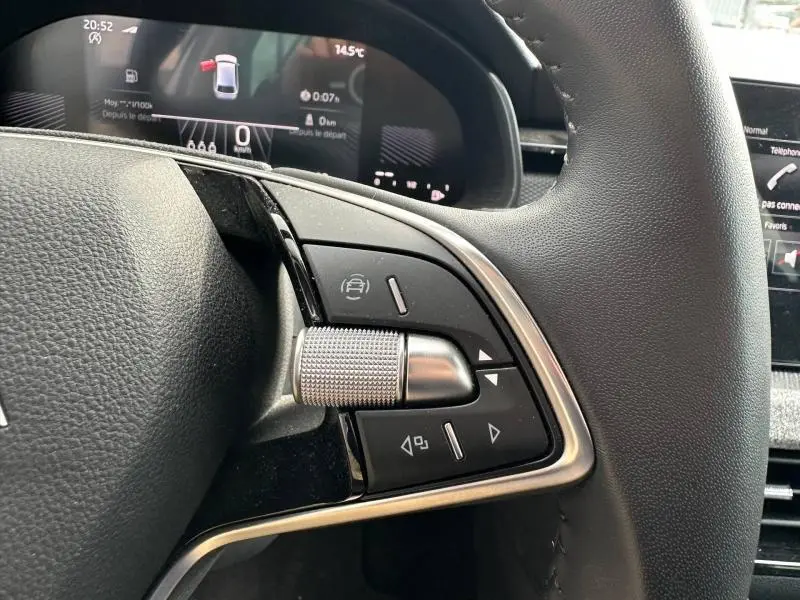 Gros plan sur les commandes à droite du volant cuir multifonction d’une Skoda Scala blanc cristal, affichage numérique en arrière-plan.