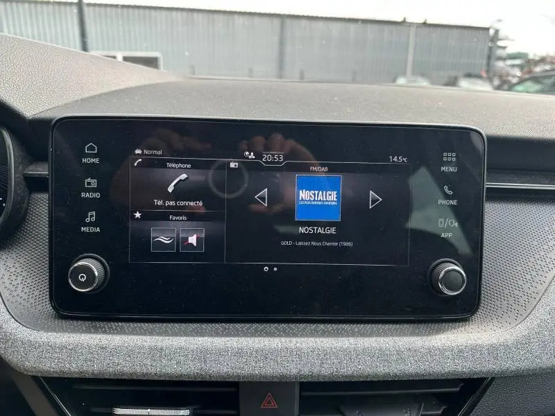 Écran tactile central du tableau de bord de la Skoda Scala blanc cristal, affichant la radio Nostalgie.