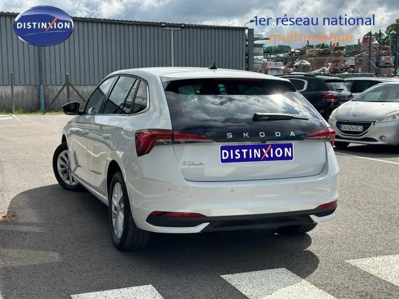 Vue 3/4 arrière droite d'une Skoda Scala blanc cristal avec feux arrière LED et jantes alu en parking extérieur.