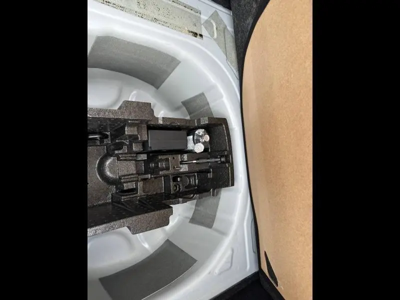 Coffre ouvert d'une Skoda Scala blanc cristal, montrant le rangement pour roue de secours et outils intégrés.