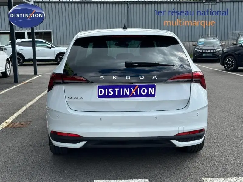Vue arrière d'une Skoda Scala blanche Cristal avec feux arrière LED et lunette arrière teintée sur parking.