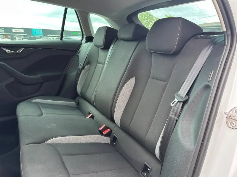 Vue latérale intérieure montrant la banquette arrière noire avec inserts gris du Skoda Scala blanc cristal.