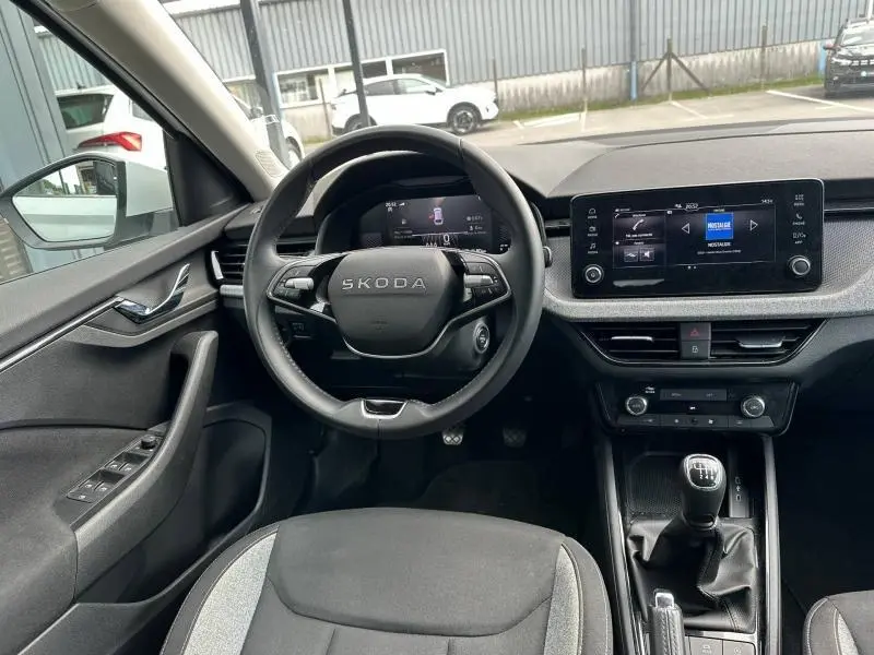 Intérieur avant de la Skoda Scala blanc cristal, vue centrée sur le volant multifonction et la console avec boîte manuelle.