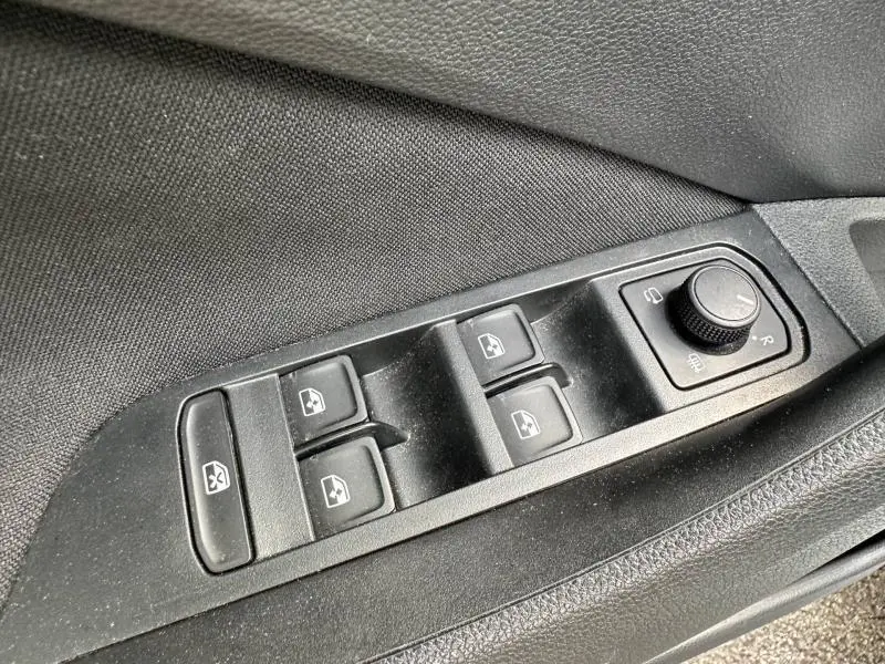 Gros plan sur les commandes des vitres électriques et des rétroviseurs côté conducteur d'une Skoda Scala blanc cristal.