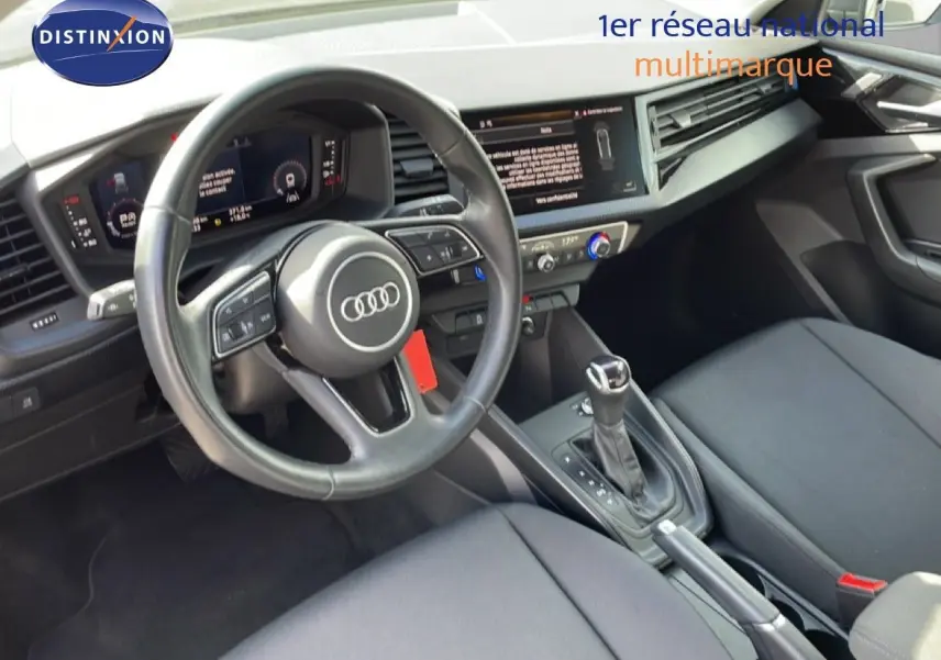 Vue intérieure de l'Audi A1 Sportback 2023, tableau de bord et volant cuir noir avec console centrale et boîte auto.