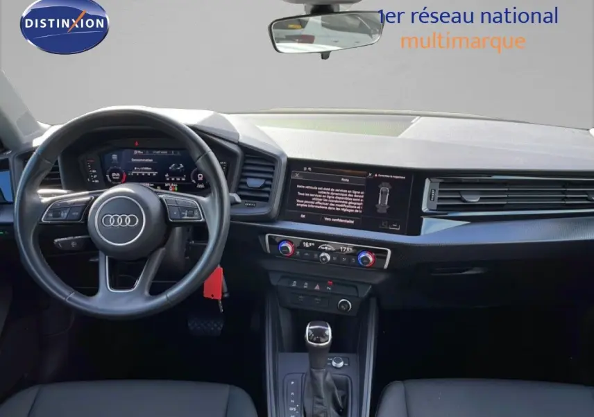 Intérieur Audi A1 Sportback 2023 vu de face, tableau de bord noir avec écran tactile et volant cuir multifonction.