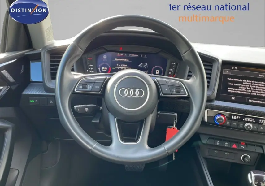Vue intérieure centrée sur le volant cuir noir d'un Audi A1 Sportback 2023 avec tableau de bord digital et écran tactile.
