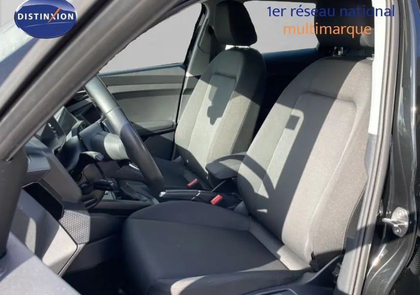 Vue intérieure côté conducteur de l’Audi A1 Sportback 2023 noir Mythe Metal, avec sièges tissu gris et volant cuir.