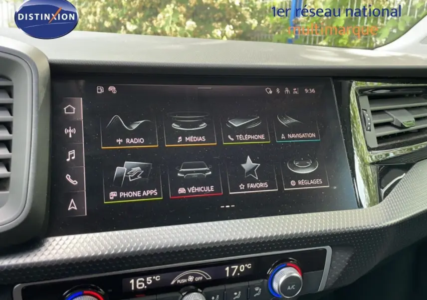 Gros plan sur l'écran tactile central et la console de climatisation d'une Audi A1 Sportback noire, intérieur moderne.