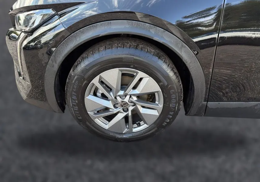 Gros plan sur la roue avant gauche d'une Peugeot 408 noire, mettant en valeur la jante alu au design moderne et le passage de roue.