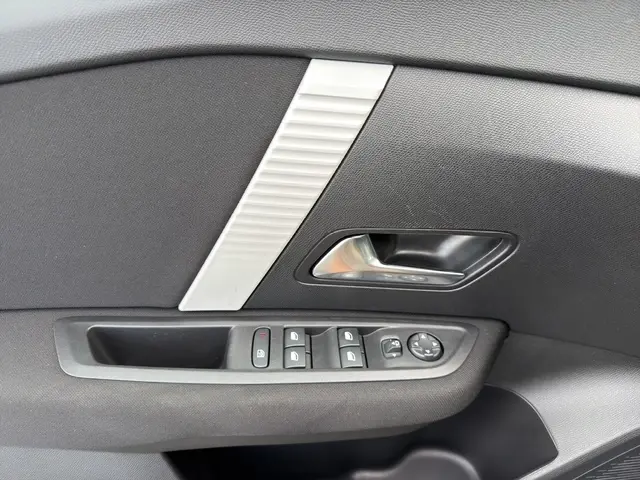 Détail intérieur montrant la poignée de porte côté conducteur et les commandes des vitres d’une Citroën C4 Hybride 2025.