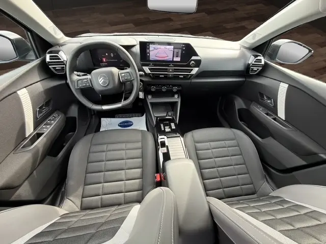 Vue intérieure avant du Citroën C4 hybride 2025, tableau de bord moderne avec écran tactile central et volant cuir multifonctions.