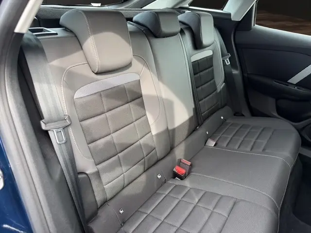 Vue intérieure côté arrière droit de la banquette arrière grise du Citroën C4 hybride 2025 avec appuie-têtes et ceinture de sécurité.