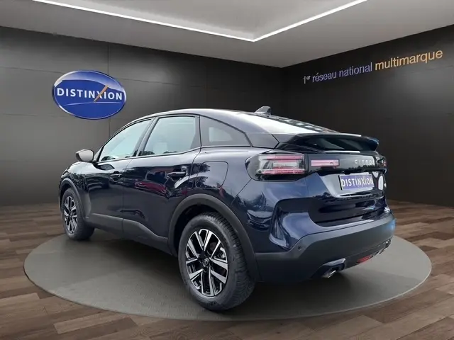 Vue 3/4 arrière droite d'une Citroën C4 hybride bleu foncé avec jantes alliage, dans un showroom intérieur.