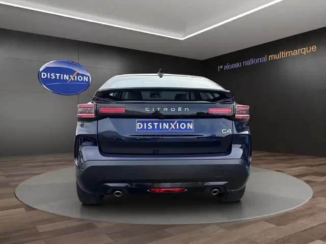 Vue arrière d'une Citroën C4 hybride bleu 2025 avec jantes alliage, feux LED et double sortie d'échappement.