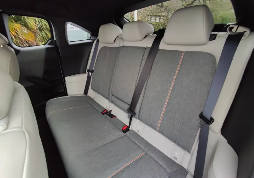 Vue intérieure arrière montrant la banquette grise et beige du Mazda MX-30 2023 avec ceintures de sécurité et appuie-têtes.