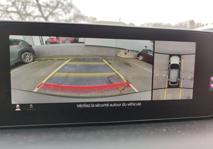 Vue caméra de recul et vue aérienne du Mazda MX-30 gris clair 2023, avec repères de stationnement visibles.