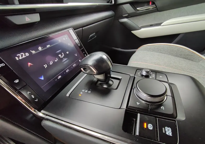 Vue rapprochée de la console centrale grise claire du Mazda MX-30 2023 avec levier de vitesse automatique et écran tactile.