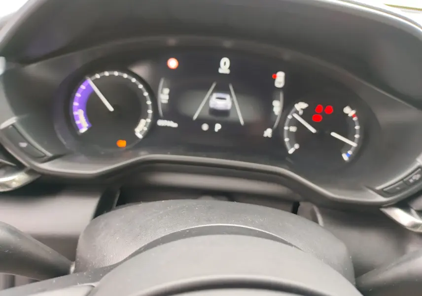 Vue rapprochée du tableau de bord numérique du Mazda MX-30 gris clair 2023, affichant les compteurs et alertes.