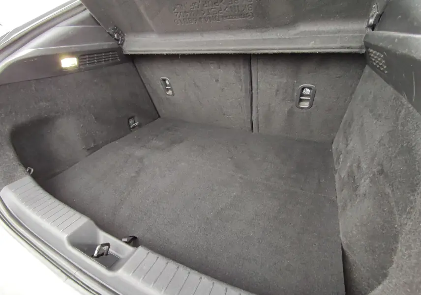 Coffre spacieux de Mazda MX-30 gris clair vu de l'intérieur, avec revêtement noir et éclairage latéral allumé.