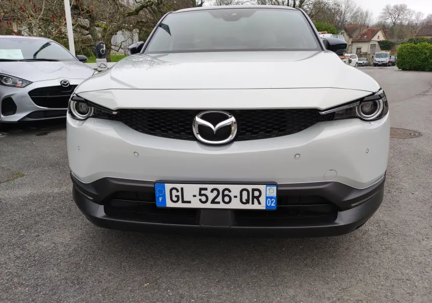 Vue frontale d'un Mazda MX-30 gris clair 2023 avec calandre noire et logo Mazda bien visible.